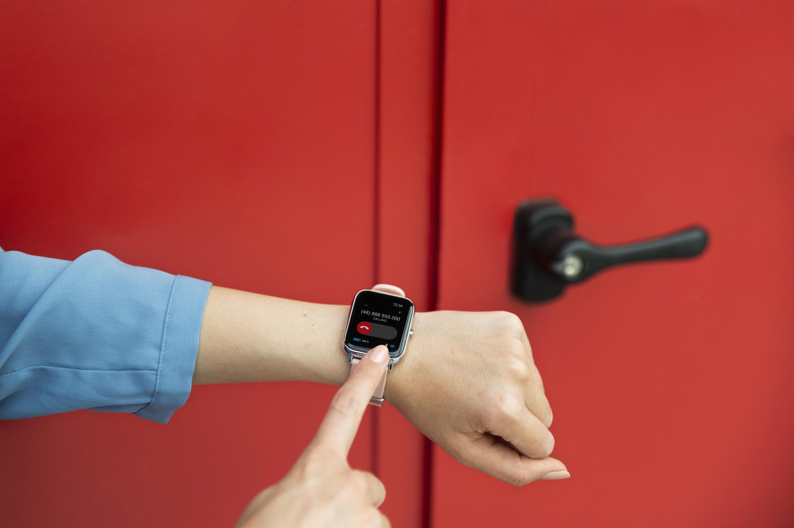 close up hand wearing smartwatch infront of door and lock